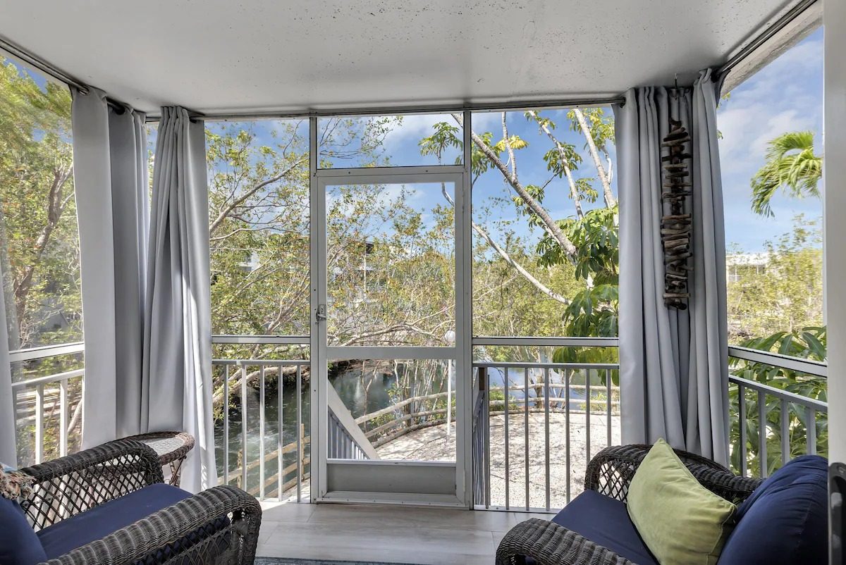 Screened balcony with wicker chairs overlooking the canal and mangroves in Key Largo