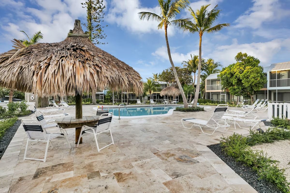 Heated pool surrounded by palms and a thatched tiki hut at Kawama Yacht Club in Key Largo