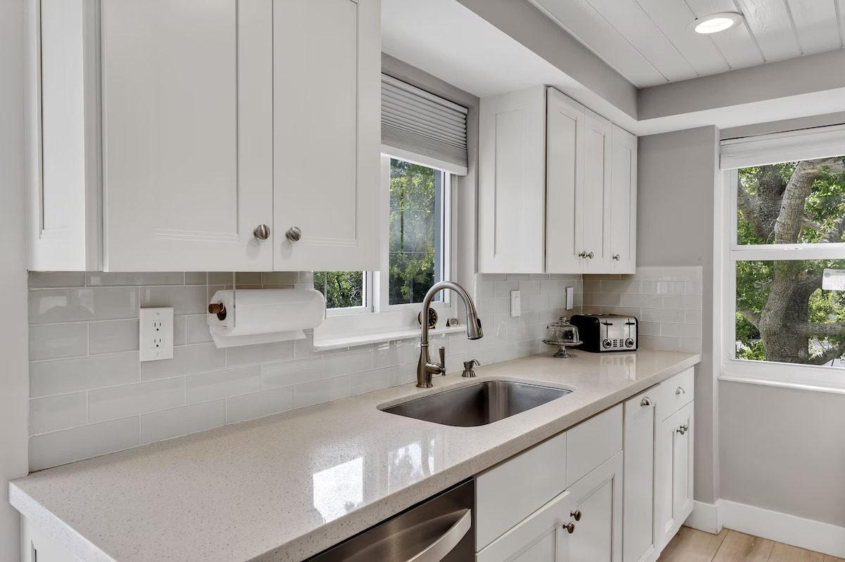 Quartz kitchen counters and sink beneath a window in the renovated Key Largo townhome